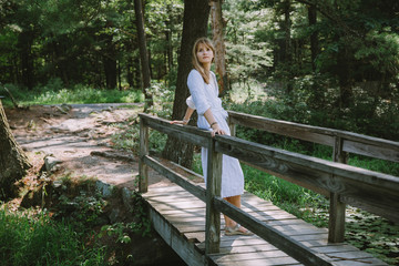 Young woman standing on the wooden bridge in the woods