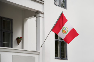 Peru flag.  Peruvian flag hanging on a pole in front of the house. National flag of Peru waving on a home displaying on a pole on a front door of a building. Flag raised at a full staff.