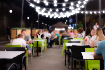 Abstract blurred image of night festival in a restaurant. Happy and relaxing people at the cafe table