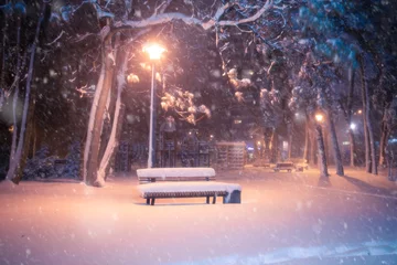 Decke mit Muster Winter Nachtwinterlandschaft mit Schneefall. Verschneite Gasse des beleuchteten Parks der Stadt