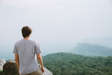 Fototapeta na wymiar young man standing on the edge of mountains