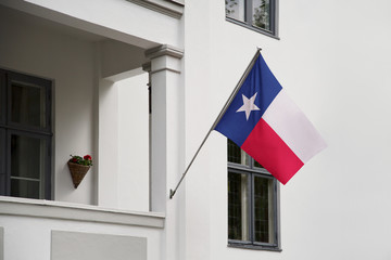 Texas flag.  Texas state flag hanging on a pole in front of the house. State flag waving on a home displaying on a pole on a front door of a building.Flag raised at a full staff. - 221951793