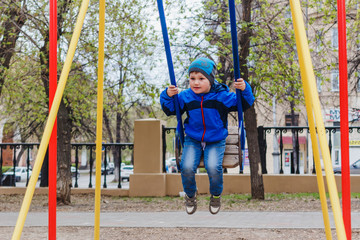 a little boy riding on a swing in the Park