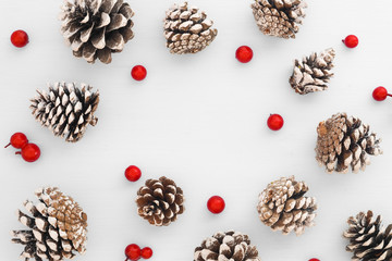 Christmas pattern made of pine cones and red berries on white background. Creative flat lay, top view design
