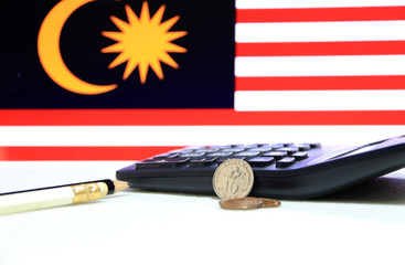 Ten sen Malaysia ringgit coin on reverse , Line image of Hibiscus rosa-sinensis and five sen with two coins of one sen, (MYR) with calculator black and white pencil on the flag background. © Achisatha