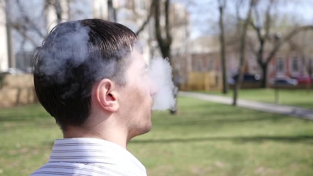 Man smoking electronic cigarette breathing out smoke slow motion