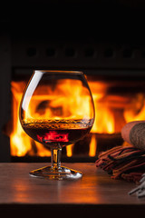 a glass of cognac in front of fireplace