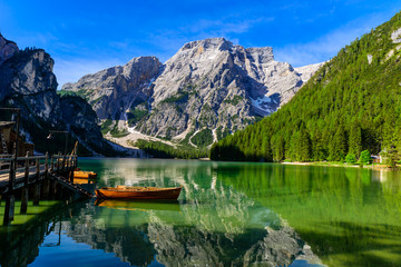 Lake Braies (also known as Pragser Wildsee or Lago di Braies) in Dolomites Mountains, Sudtirol, Italy. Romantic place with typical wooden boats on the alpine lake.  Hiking travel and adventure. - obrazy, fototapety, plakaty