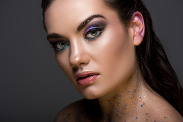 fashionable young woman posing with glitter makeup, isolated on grey