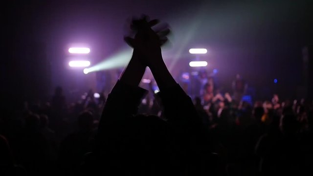 Fan spectator clapping hands up in air enjoying music concert light lumiere