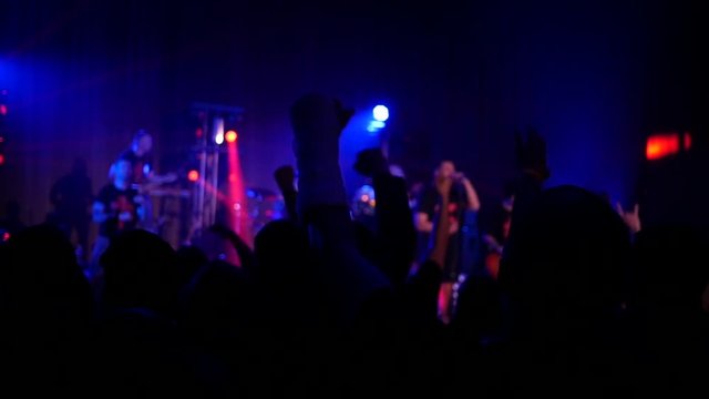 Cheering silhouettes crowd fan spectators rais hands up in air enjoying concert