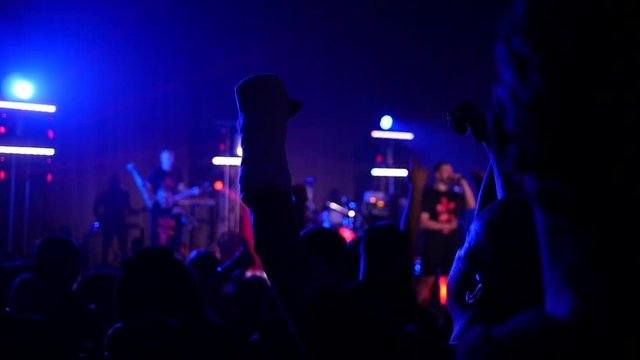 Cheering silhouettes crowd fan spectators rais hands up in air enjoying concert