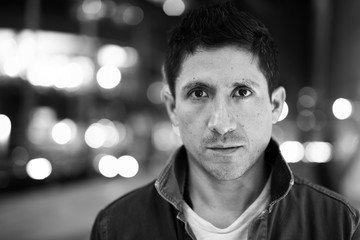 Portrait of Hispanic man against view of the city in black and white