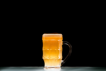mug of light fresh beer at table on black background, minimalistic concept