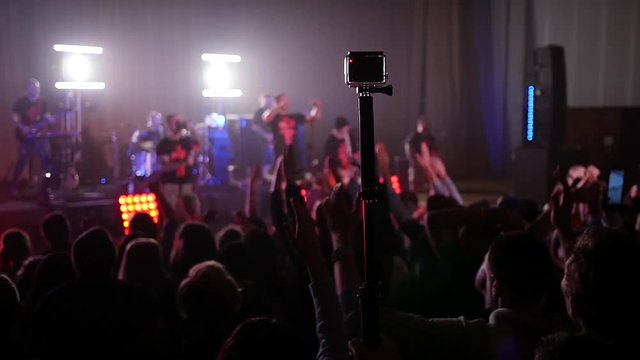Crowd fan spectators silhouettes raise swaying hands at concert light lumiere