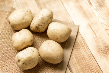 Raw potato tubers on a wooden background.