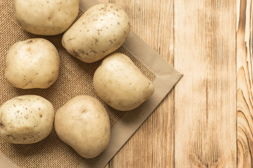 Raw potato tubers on a wooden background.