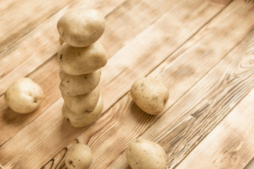 Raw tubers of potatoes in the form of a pyramid on a wooden background.