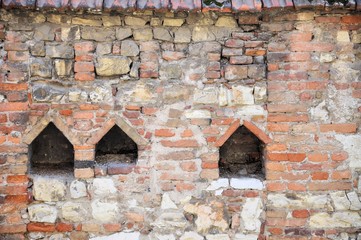 Medieval wall of stone and bricks with housing for pigeons.