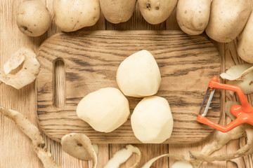 Raw tubers peeled potatoes on a wooden background.