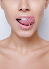 Beautiful woman sticking out her tongue and showing her young piercing