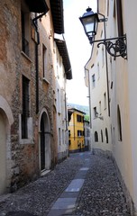 Medieval halley with stone floor and old iron street lamp. Brescia, Italy.