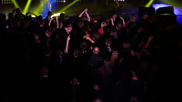 Dancing cheering crowd fan spectators rais hands at concert lumiere spot lights