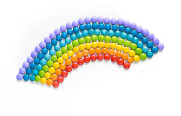 Rainbow of multicolored candy dragees on white background