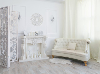 White interior of a photo studio with a fireplace and a sofa in the center
