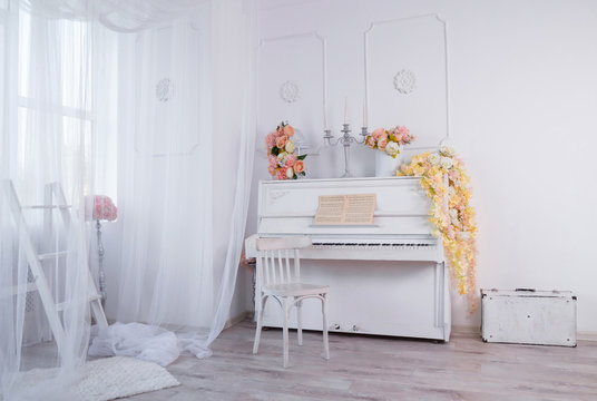 White interior of a photo studio with an old upright piano in the center