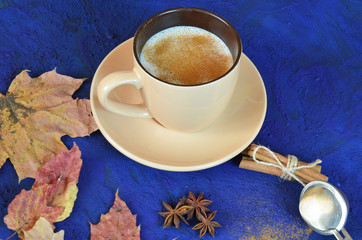 Autumn cappuccino composition. coffee cup top view with foam, cloves, cinnamon, autumn fallen...
