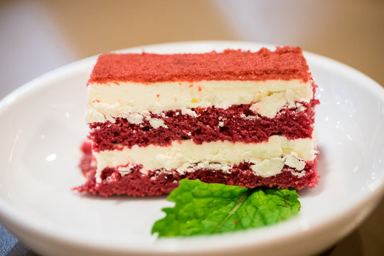 Close up red velvet cake in the white dish with peppermint leaf. image for background, wallpaper and copy space. high calories and carbohydrate.