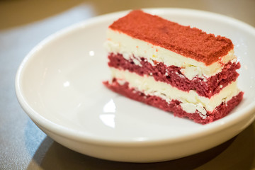 Close up red velvet cake in the white dish with peppermint leaf. image for background, wallpaper and copy space. high calories and carbohydrate.