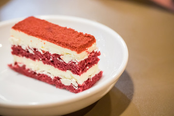 Close up red velvet cake in the white dish with peppermint leaf. image for background, wallpaper and copy space. high calories and carbohydrate.