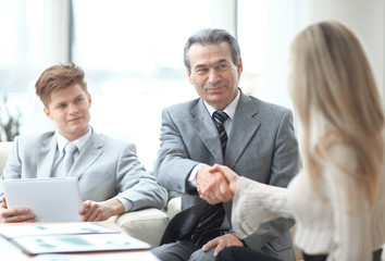 handshake of a businessman and the business woman behind a Desk