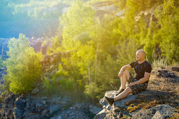 traveler sits and enjoys by nature around him on a cliff. A tourist rests from long mountain walk
