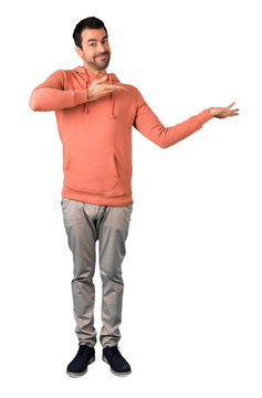 Full body of  Man in a pink sweatshirt presenting and inviting to come on isolated white background