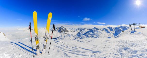 Ski in winter season, mountains and ski touring equipments on the top in sunny day in France, Alps above the clouds. - obrazy, fototapety, plakaty
