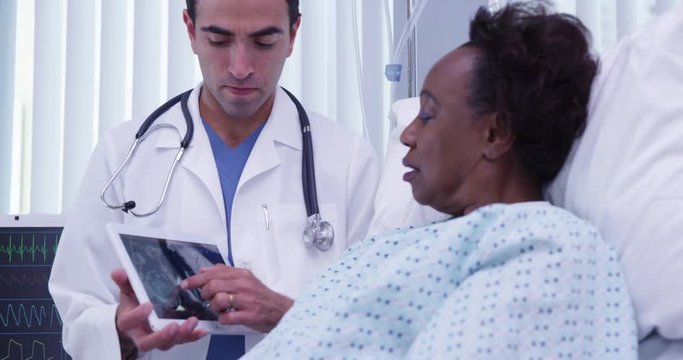 Close up of medical doctor showing ct scan results of patients cranium. Senior African woman viewing ct-scan of brain on portable tablet