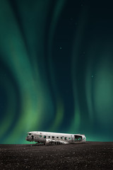green northern lights over the wreck of a white airplane
