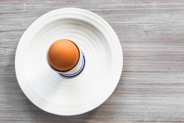 brown egg in cup on white plate on gray board