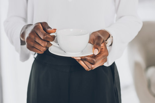 cropped image of stylish african american businesswoman holding cup of coffee in office
