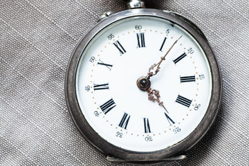 shabby pocket watch on gray textile background