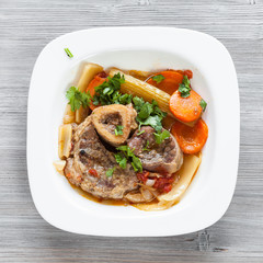 top view of italian dish Ossobuco on gray board