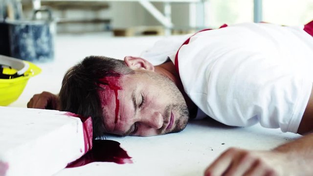 A man worker with bleeding wound on head lying on the floor after accident.