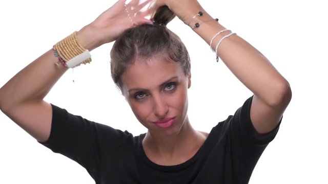Beautiful young woman tying her hair in ponytail making hairdo isolated on white background
