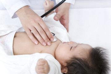 Obraz na płótnie Canvas 病院で胸に聴診器を当て診察を受ける新生児の赤ちゃん。子供の健康診断、健診,定期健診,診察,病気イメージ