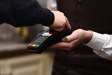 Cashier holds credit card reader on defocused background