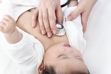 Obraz na płótnie Canvas 病院で胸に聴診器を当て診察を受ける新生児の赤ちゃん。子供の健康診断、健診,定期健診,診察,病気イメージ