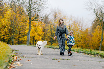 Mom and son walking their dog in the park in the fall